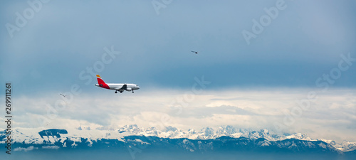 Passenger plane fly above Dolomites mountains covered by snow.