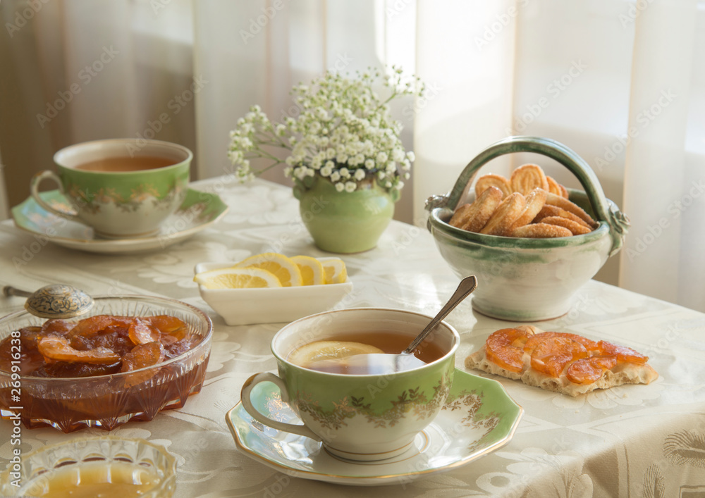 Delicious fresh breakfast for two. Tea with lemon, apple jam and biscuits Delicious fresh breakfast for two. Tea with lemon, apple jam and biscuits
