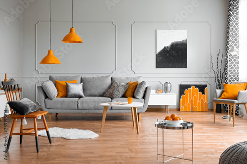 Orange accents in a grey living room interior photo