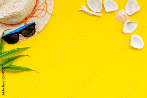 Summer travaling to the sea with straw hat, sun glasses, shells on yellow background top view mock up