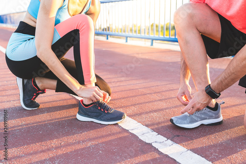 Hispanic Couple Tying Their Trainer Shoes After Running Together Outdoors.