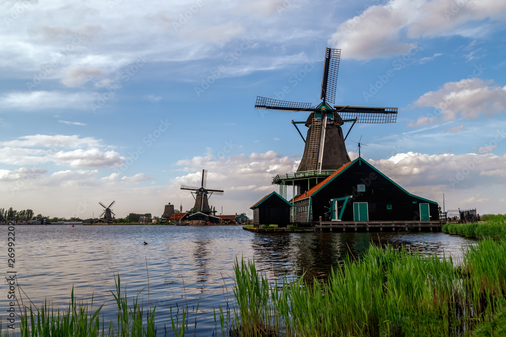 Holland countryside landscape with traditional dutch windmills in sunny day in the historic village of Zaanse Schans, a neighbourhood of Zaandam, near Amsterdam in the Netherlands.