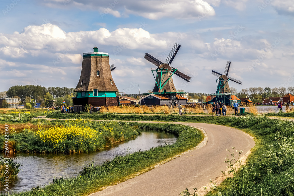 Holland countryside landscape with traditional dutch windmills in a sunny day in the historic village of Zaanse Schans, a neighbourhood of Zaandam, near Amsterdam in the Netherlands.