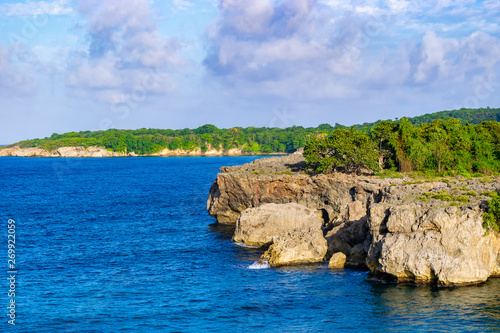 Cliff side/cliffside coastline view on tropical Caribbean island ocean. Scenic mountainous rock formations from sea erosions along coast of Portland Jamaica. Sunny summer day on coastal countryside.