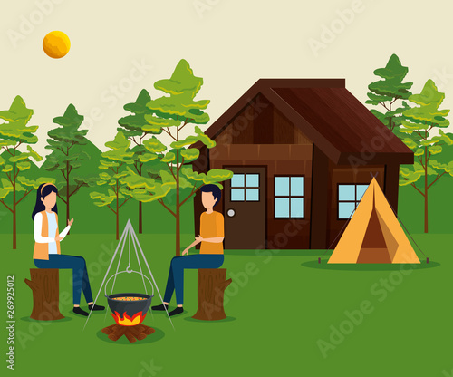 woman and man sitting in the tree trunk with cabin and camp
