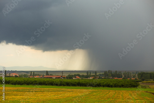 Thunderhead covers the Balkans. Downpour is approaching agricultural land. Bulgarian villages before the rain.