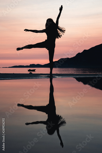 Silhouette of young woman dancing at sunset