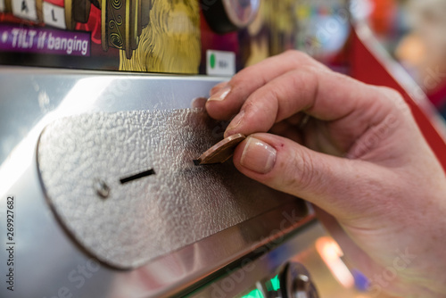 A woman plays a 2p tuppeny nudger machine in a funfair at a British seaside resort. photo