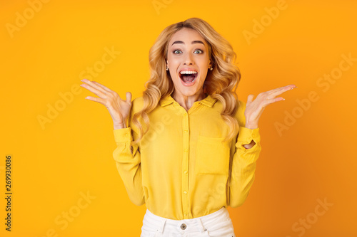 Excited Millennial Woman Screaming Over Yellow Background photo