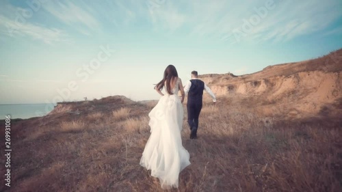Romantic wedding moment, couple of bride and groom hug while on a walk in the park. Loving wedding couple outdoor.