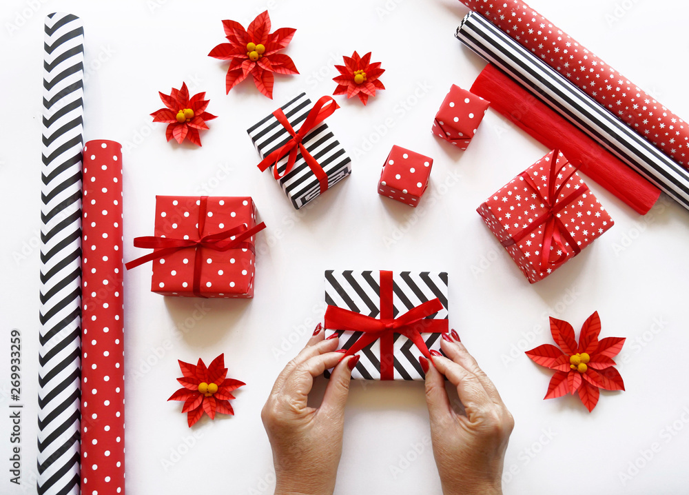 Fototapeta premium The process of packaging Christmas gifts. Poinsettia. New Year.