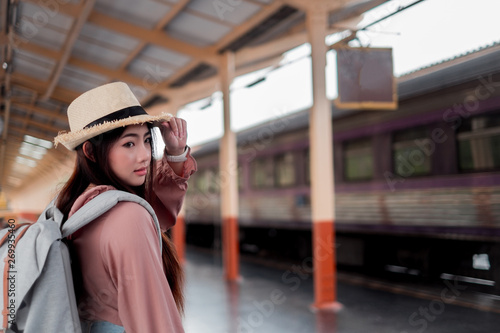 Smiling woman traveler holding hat with backpack on holiday relaxation at the train station,relaxation concept, travel concept