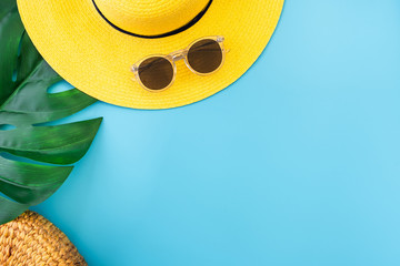 summer blue banner with yellow hat ,sunglasses and monstera leaf on blue background top view