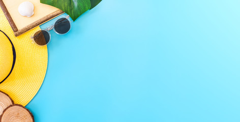 summer blue banner with yellow hat ,sunglasses,seashell,frame and monstera leaf on blue background top view.