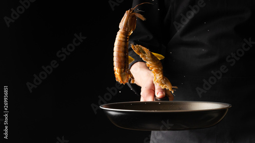 Chef prepares sea food, mantis shrimp, East Asian cuisine, dilikates, on a black background, horizontal photo, banner photo