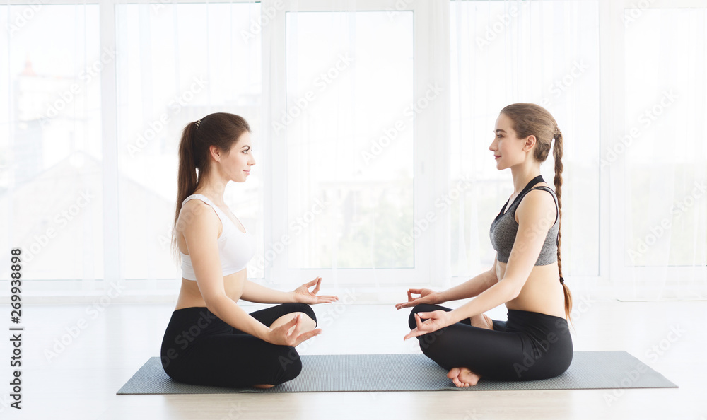 Young women concentrating in Lotus pose in front of each other Young women concentrating in Lotus pose in front of each other
