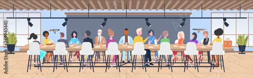 businesspeople group brainstorming sitting at round table during conference meeting mix race coworkers discussing new project in co-working open space interior flat horizontal