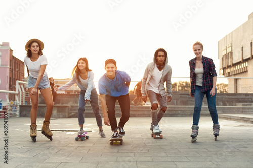 Bilde på lerret Group of diverse young people skateboarding and rolling in urban area