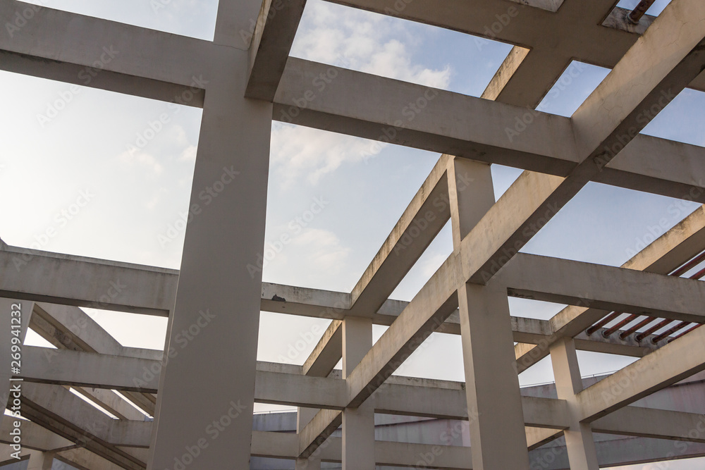 Looking up at the concrete pillars and beams at the top of modern high-rise buildings under the blue sky background, beautiful architectural art style Looking up at the concrete pillars and beams at the top of modern high-rise buildings under the blue sky background, beautiful architectural art style