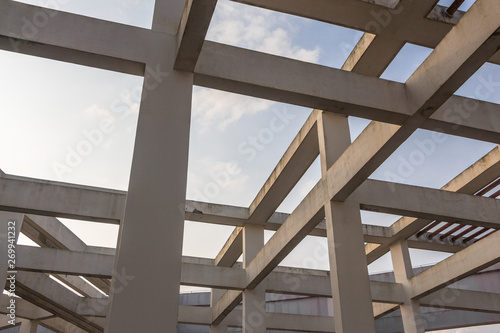 Looking up at the concrete pillars and beams at the top of modern high-rise buildings under the blue sky background, beautiful architectural art style