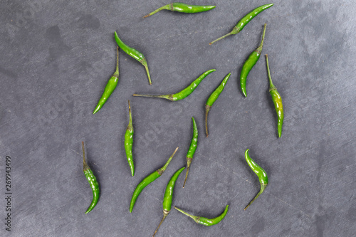 Fresh birds eye green chilli scattered top view on black slate stone background photo