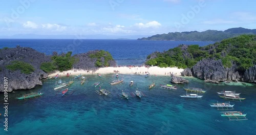 Flyby aerial view of Lahos Island crowded with tourists and stationed bangka boats, Caramoan Islands Philippines photo