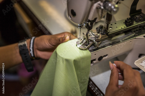 seamstress on a sewing machine makes a shirt in the sewing workshop. close-up partial view of seamstress working.