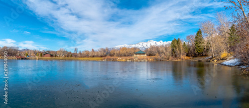 Winter view of an icy lake reflecting the radiant blue sky with clouds