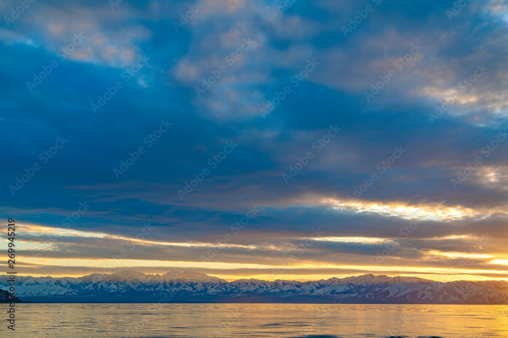 Scenic panorama of a lake and snow capped mountain under a striking cloudy sky