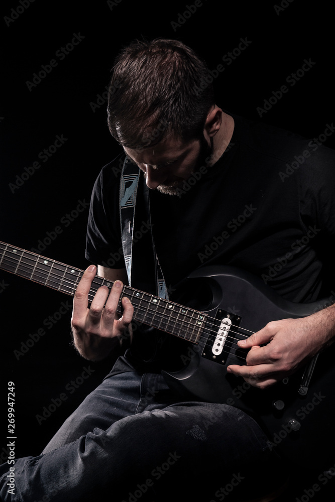 Obraz premium one man, playing guitar, dark and moody rock musician. Black and white image.