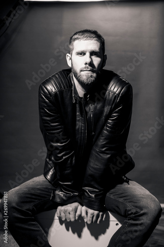 one man, moody dark, rock musician portrait, posing in studio. black and white image.
