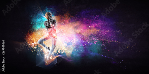 Modern female dancer jumping in hoodie with colourful splashes background. Mixed media © Sergey Nivens