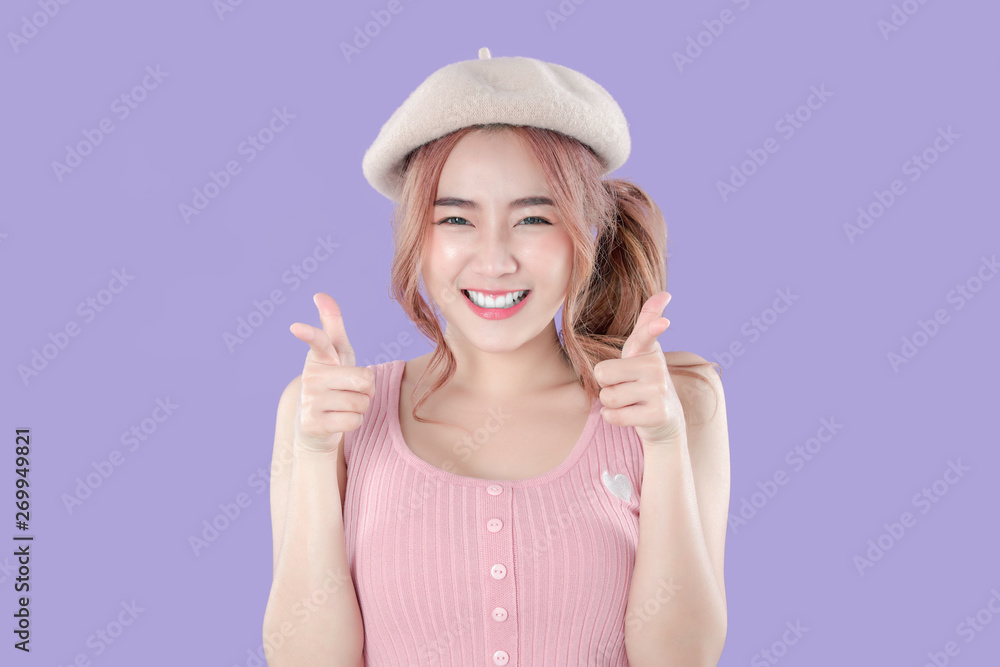Korean woman point to special deals & discounts of promotions, tank top with beret hat, purple background Korean woman point to special deals & discounts of promotions, tank top with beret hat, purple background