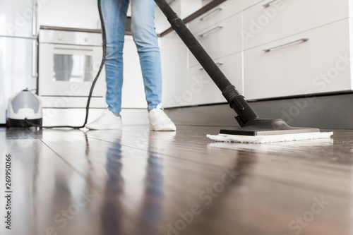 professional home cleaning service. Woman washes the floor with a steam mop