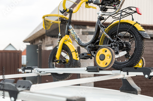 Bicycle transportation - a children's bicycle on the roof of a car against the sky in a special mount for cycling. The decision to transport large loads and travel by car © xartproduction