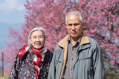 Happy old couple smiling in a park.mature couple with cherry blossom sakura tree.seniors lover family and healthcare concept.