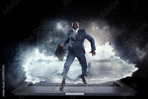 Black businessman running on laptop keybord followed by wave of pouring water out of laptop screen