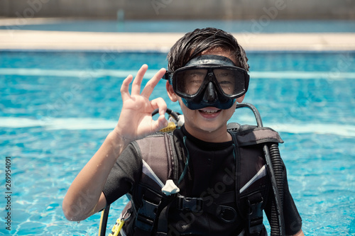 Young little Asian tween preteen boy scuba diver showing ok hand signal, diving lessons for beginners, teen travel, Sign Language