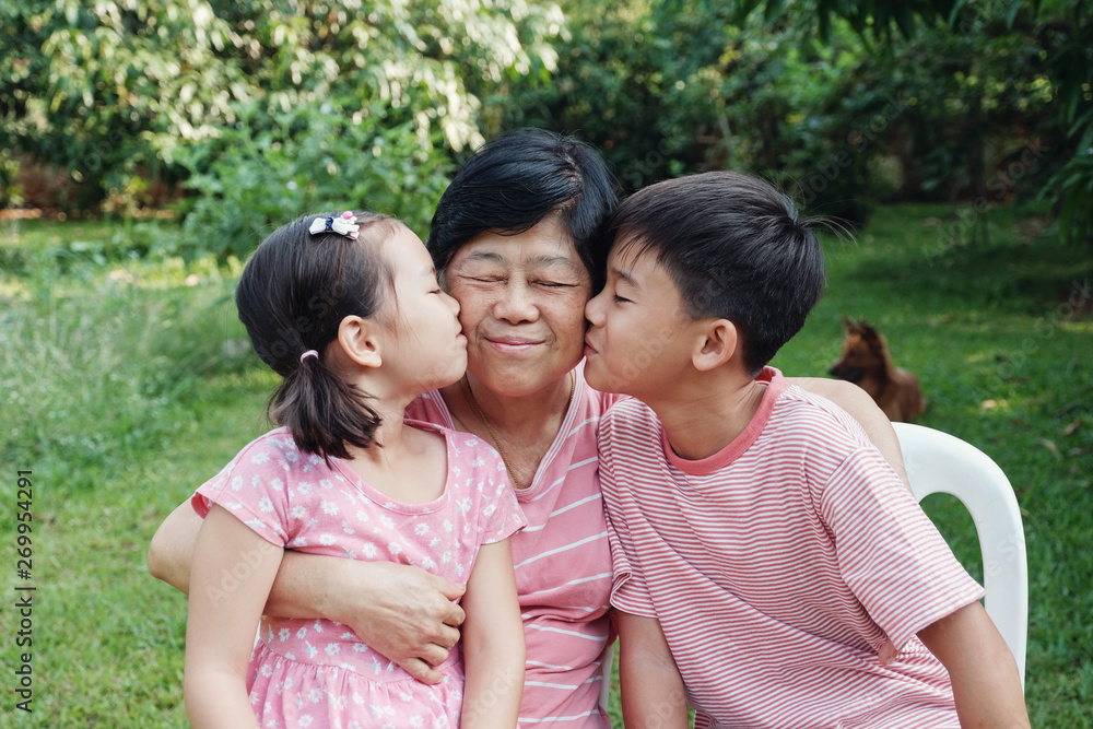Asian grandchildren kissing their grandmother in the park, Happy Asian senior woman, multigenerational concept Asian grandchildren kissing their grandmother in the park, Happy Asian senior woman, multigenerational concept