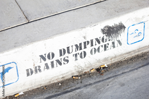 Foto A rain drainage area with a sign that says No Dumping Drains to ocean