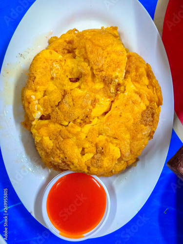 Traditional Thai crispy crab omelet in a white plate with tomato sauce.