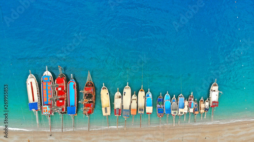 Boats in the sea, top view. Aerial view of colorful boats standing abreast on the shores of the Mediterranean sea in azure water. Nautical background and summer traveling concept.