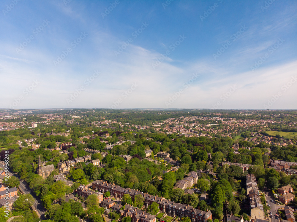 Aerial footage of the Leeds town of Headingley, the footage shows Terrence houses and homes and the town centre in the background with roads and traffic, taken on a beautiful sunny day.