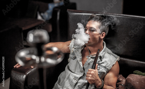 Man is blowing smoke in night club. photo