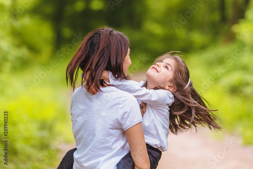 Young mom holds and spins her little girl in forest