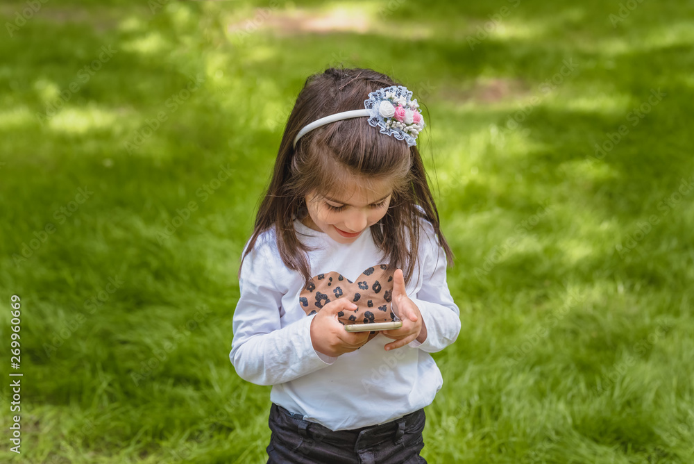cute little girl in casual clothes holds mobile phone cute little girl in casual clothes holds mobile phone