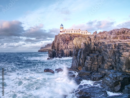 Lighthouse building with tower against to evening sky. Popular Neist Point, photo