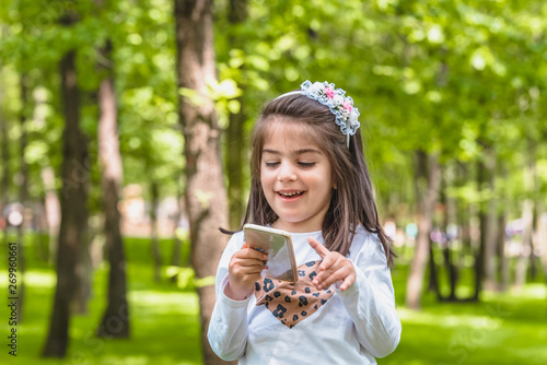 cute little girl in casual clothes holds mobile phone