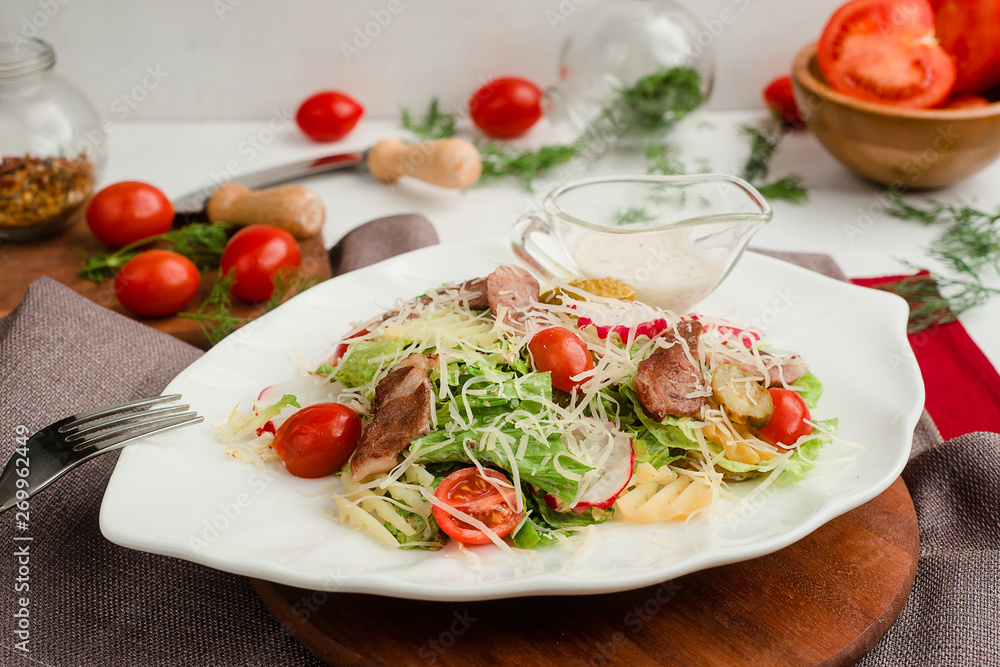 Salad with roasted meat, radish, lettuce, cherry tomatoes, cheese, and pickled cucumbers. Cafe menu on a wooden background in warm colors.