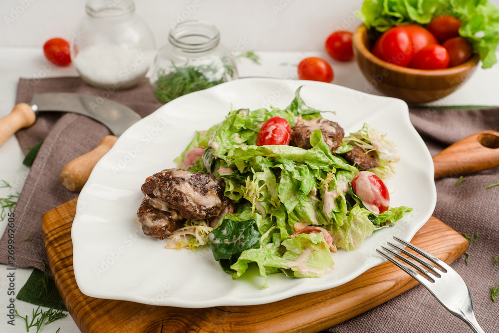 Salad with beef, lettuce, cherry tomatoes, and mayonnaise dressing. Cafe menu on a wooden background in warm colors with copy space.